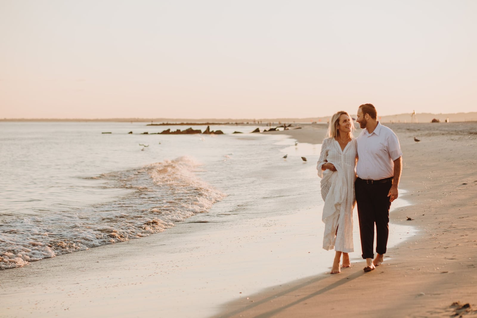 A couple walking along the beach in everyday clothes