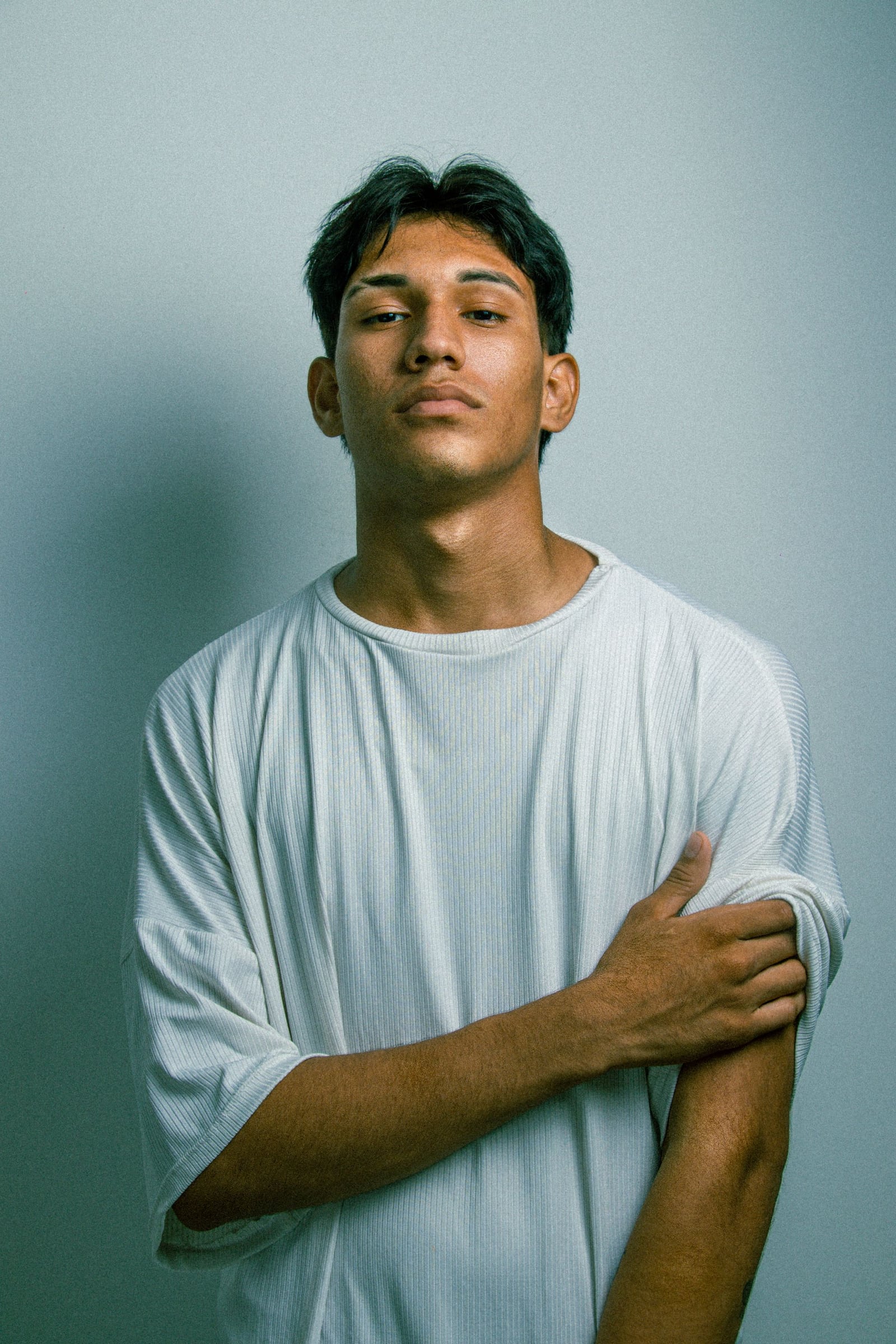 A man with folded arms against a soft gray-blue background