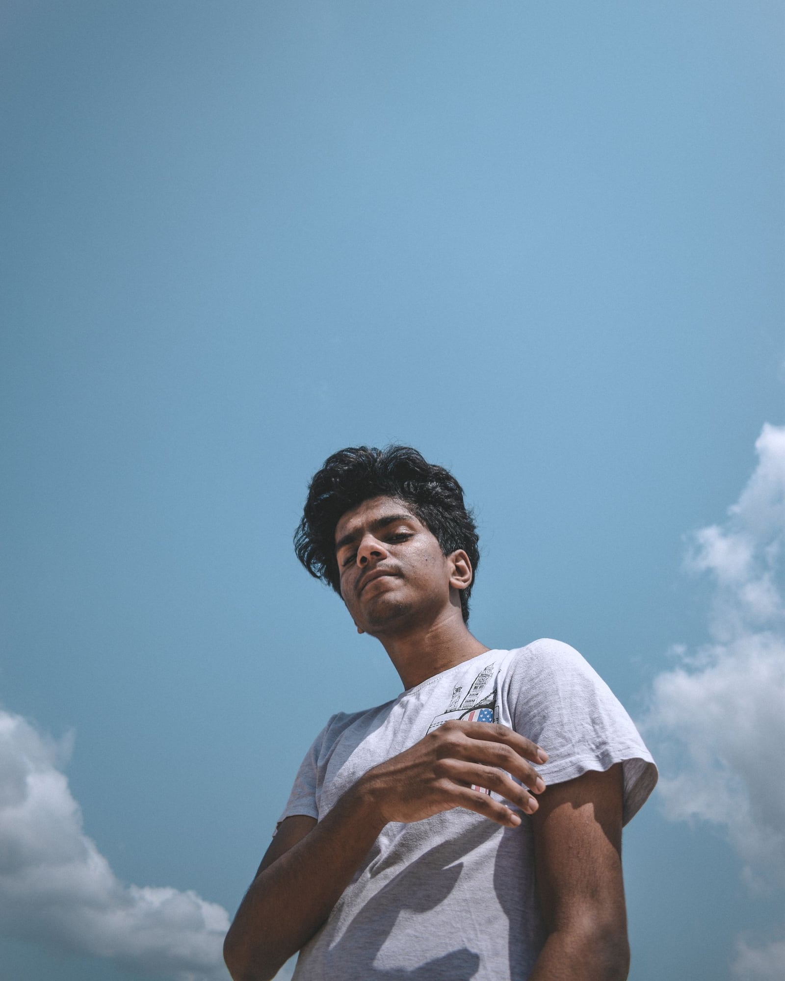 A man in a white T-shirt beneath a soft blue sky