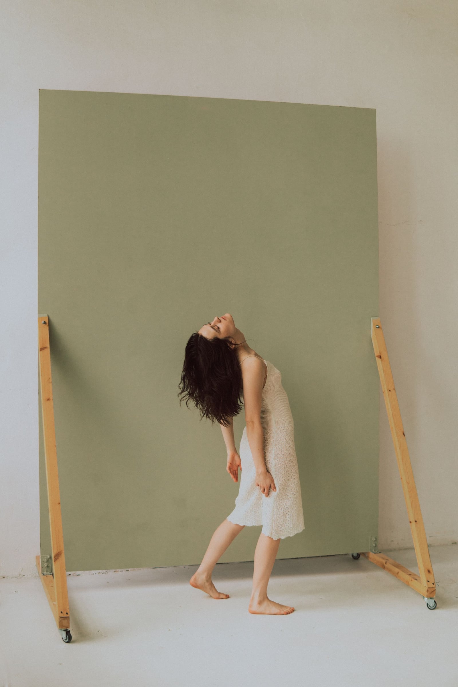 An expressive full-body portrait in front of a muted green studio backdrop