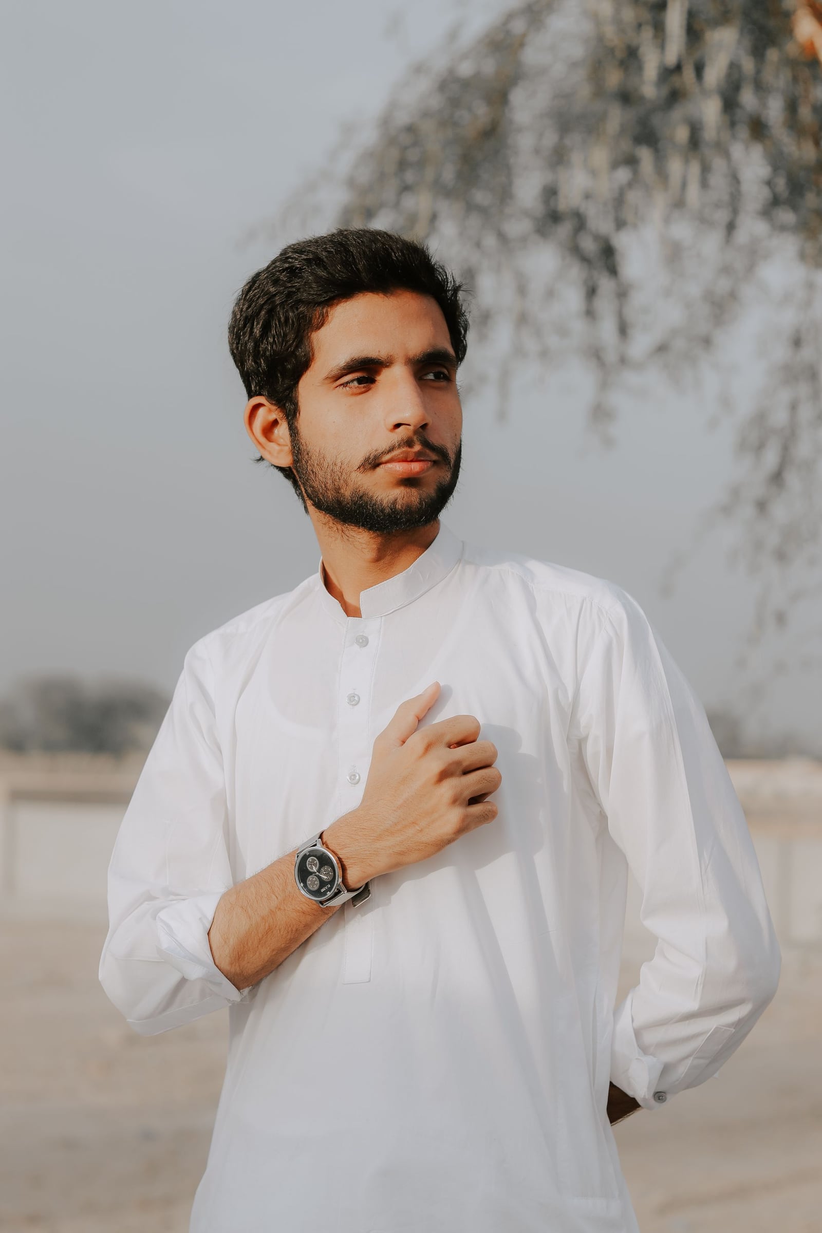 A man in white clothes outdoors beneath a pale sky