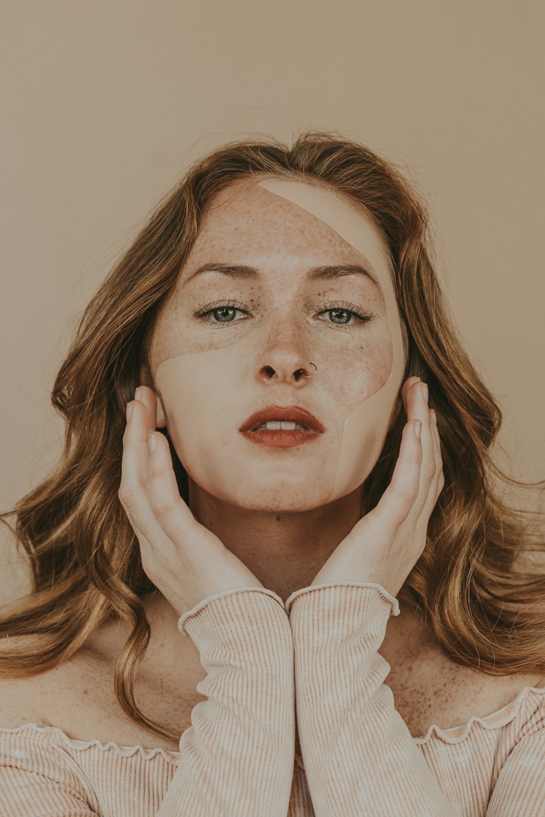 A freckled face framed by hands