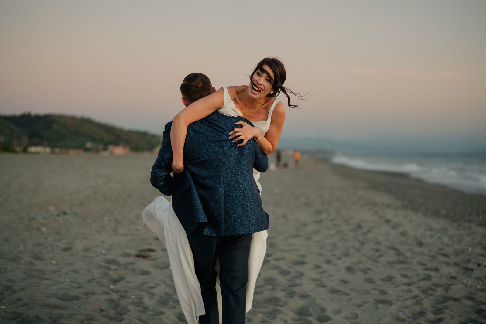 A joyful newlywed couple embracing on a sandy beach.