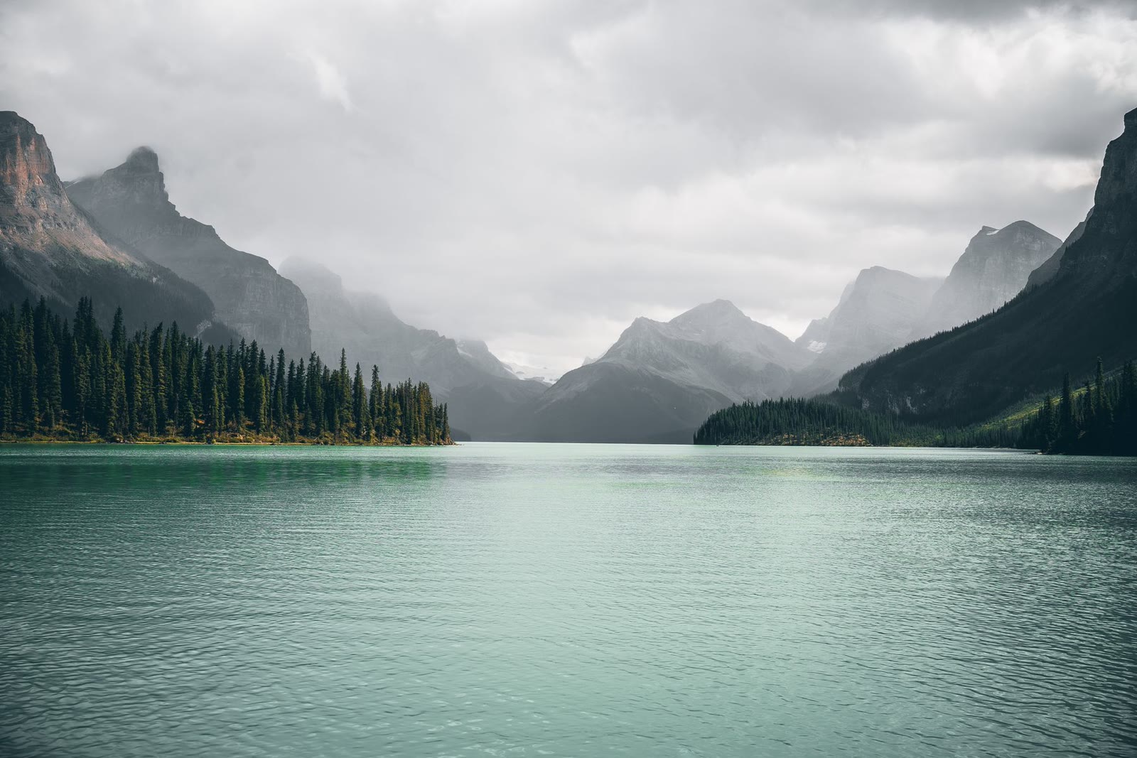 A turquoise alpine lake beneath a rugged mountain range.