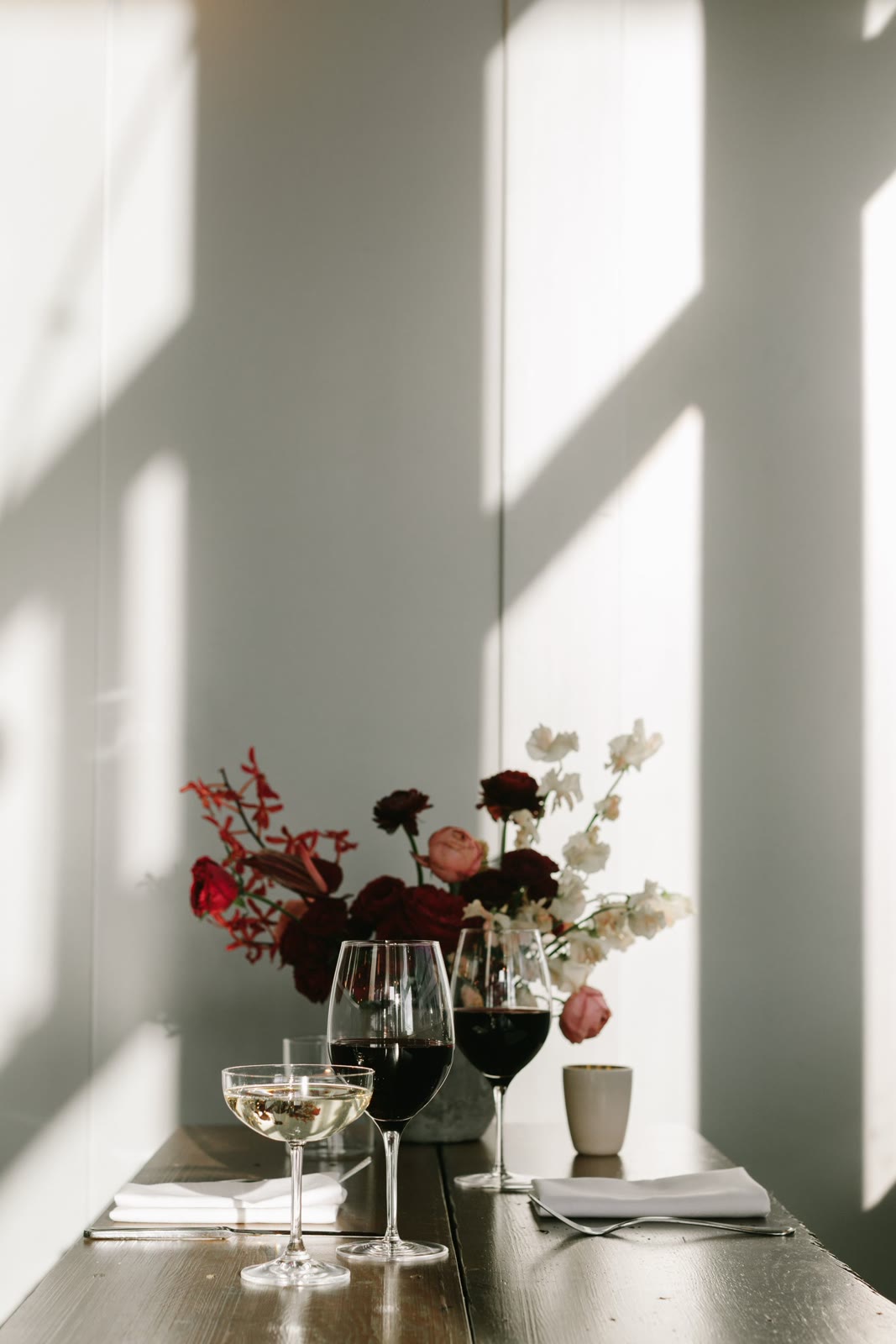 An elegant dining table with wine glasses and flowers in soft light.
