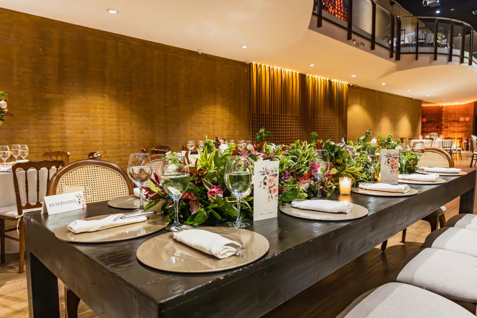 A warmly lit restaurant set with flowers and tableware.