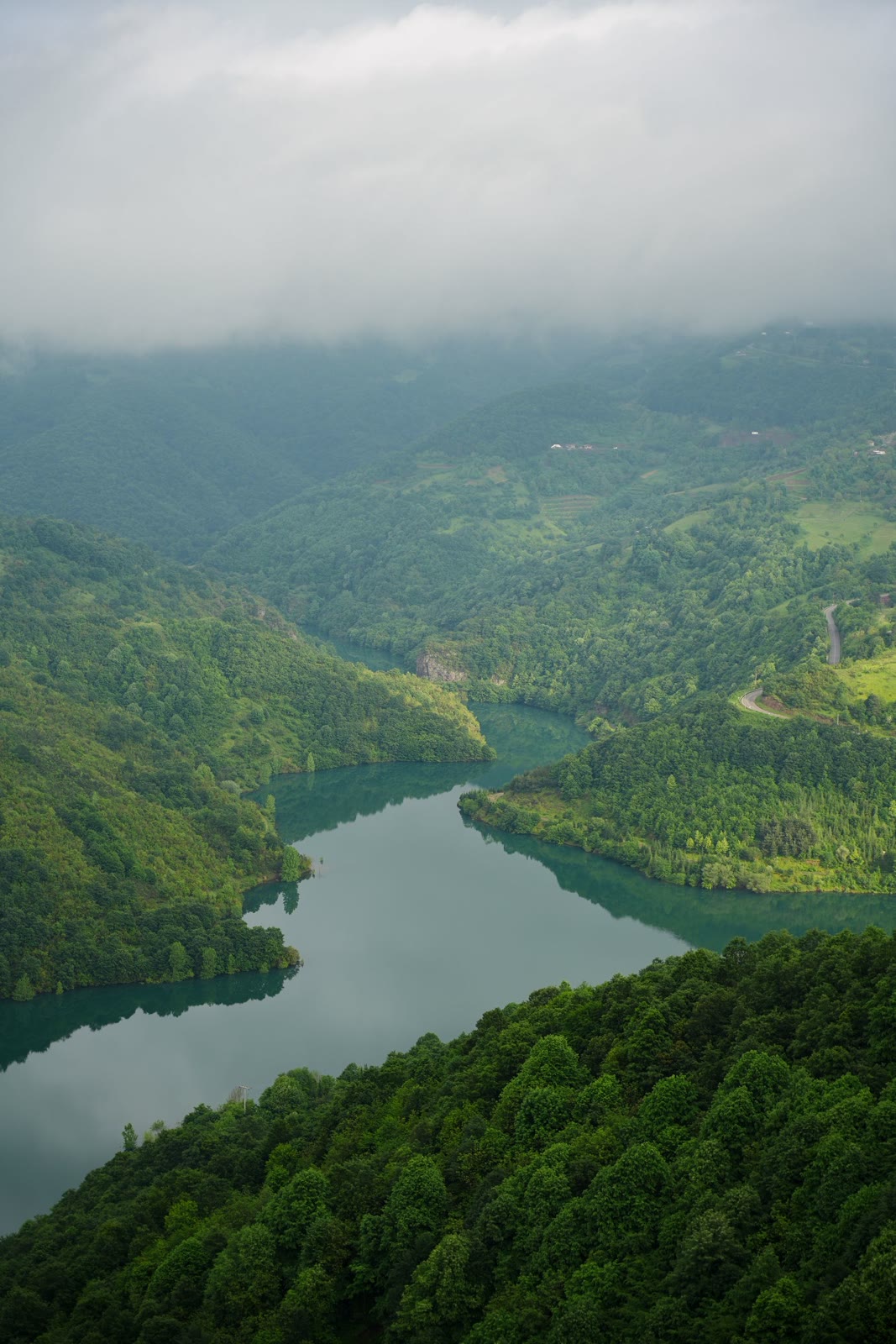 A calm mountain lake beneath wooded hills